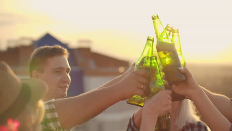 Russian-people-clinks-glasses-and-drinks-beer-from-green-bottels-on-the-party-with-friends-on-the-roof